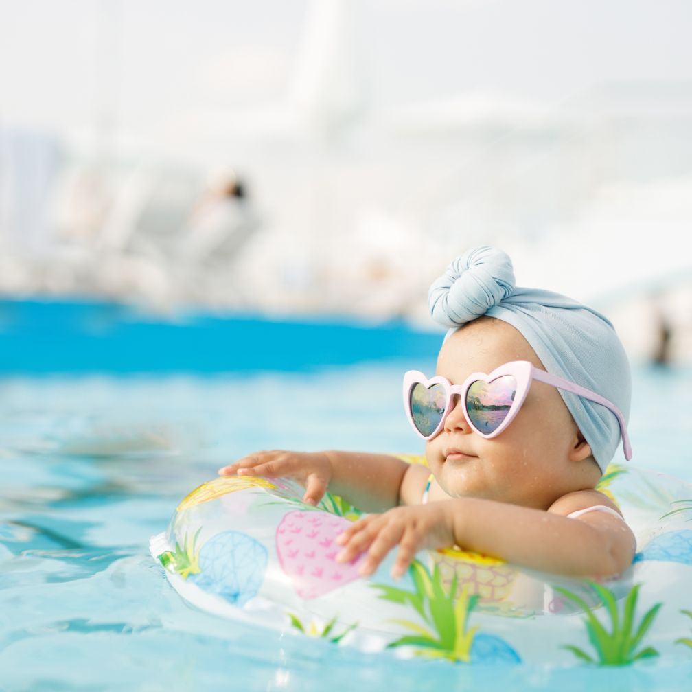 Baby mit Schwimmreifen und Sonnenbrille in einem Schwimmbecken